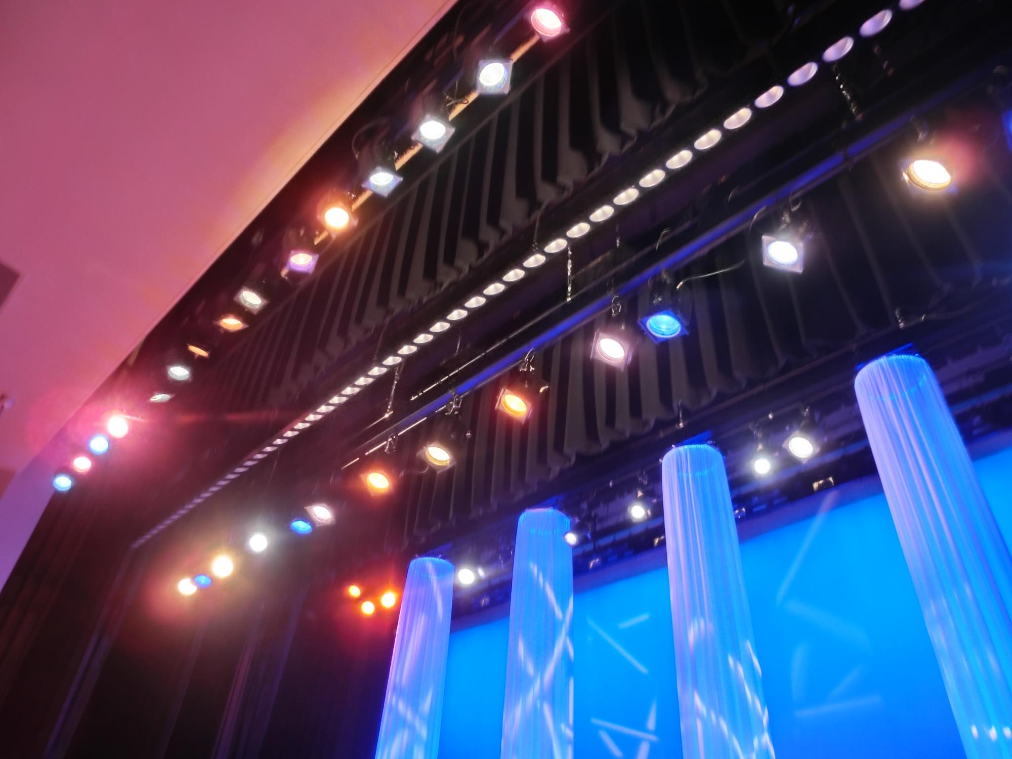 天井幕の間に設置された照明が水色に模様が入った演出をしている大ホールの舞台の写真