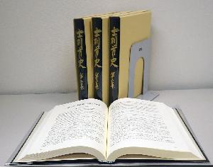 3冊の士別市史第三集がブックスタンドに立てかけられ、手前に1冊の本が開かれた状態で置かれている写真