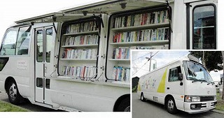 車の荷台に沢山の本が並べられている白色の移動図書館車「ヨムヨム号」の写真、白色の移動図書館車「ヨムヨム号」を右斜め前から写した写真