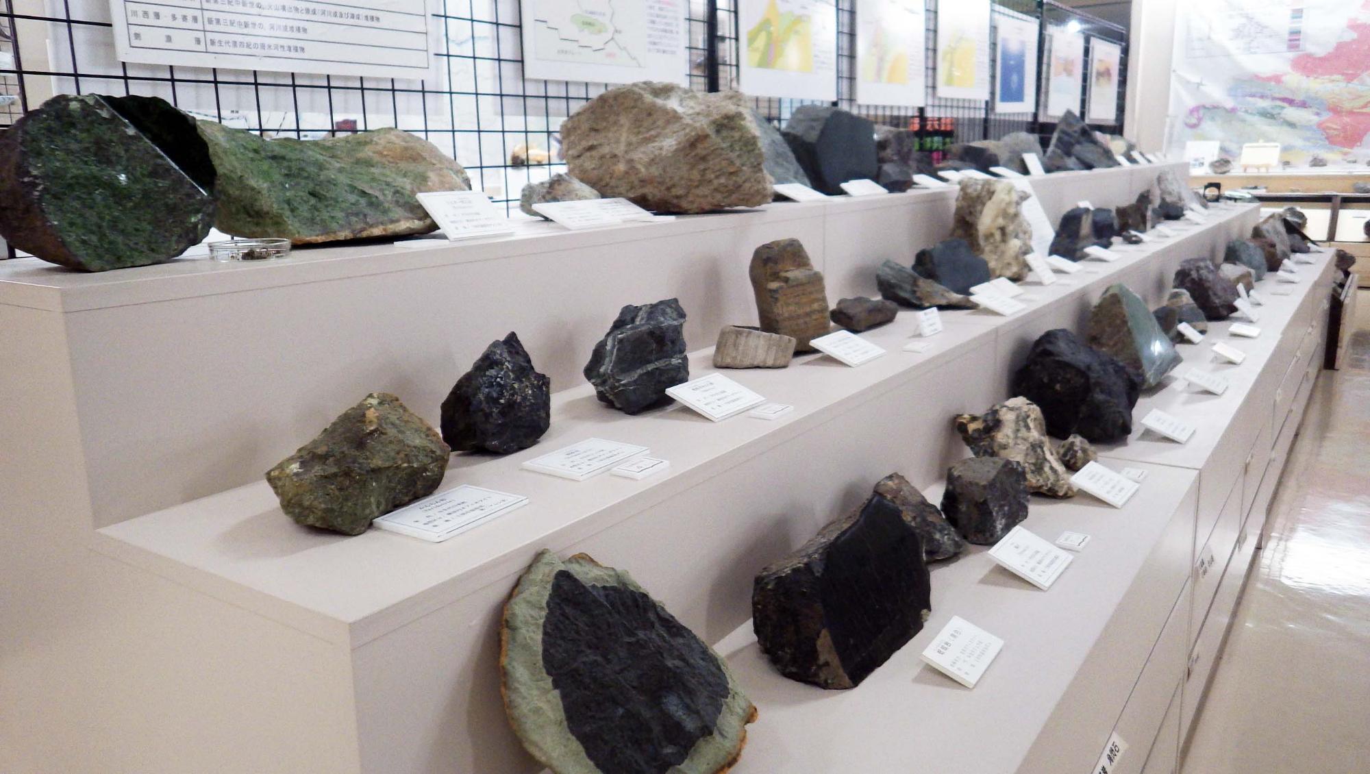 様々な種類のたくさんの岩石が3段の展示台に並べられている写真