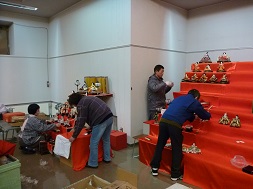 雛壇にひな人形を並べる作業をしているボランティアの方々の写真