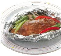 白皿の上に生鮭と玉ねぎ、パプリカなどの野菜をホイルで包み味噌などの調味料を塗り焼いて完成した鮭とたっぷり野菜のホイル焼きが置かれた写真