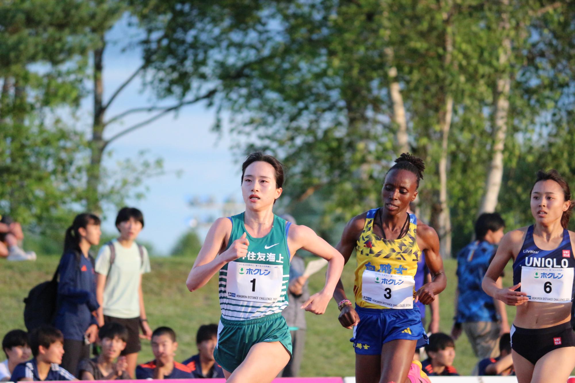 ホームストレートを集団で走る男子選手の写真