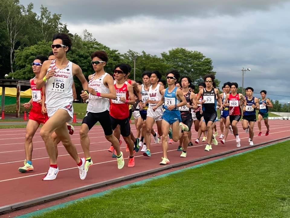 ホームストレートを集団で走る男子選手の写真