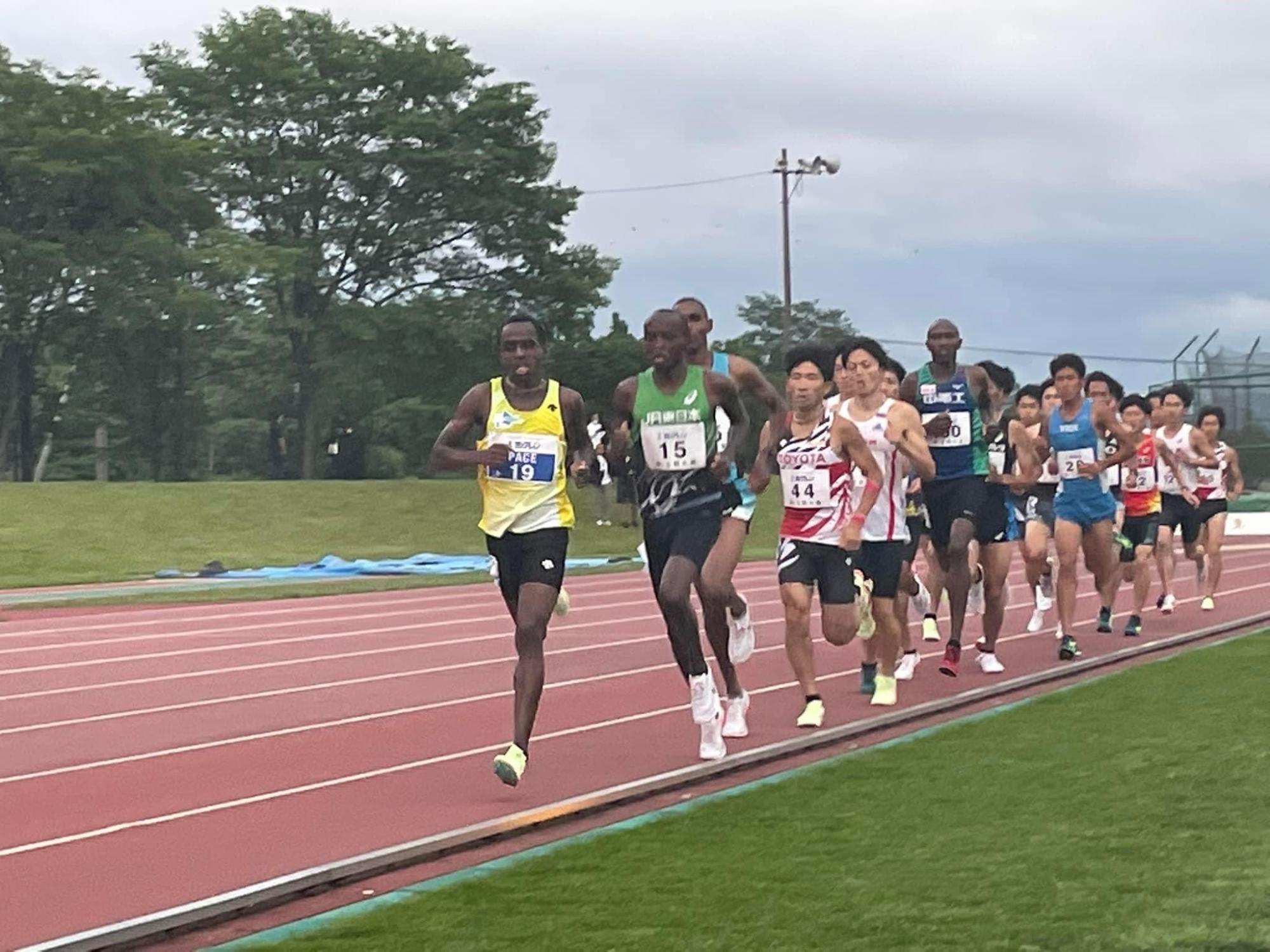 ペースメーカーの後ろを集団で走る男子選手の写真