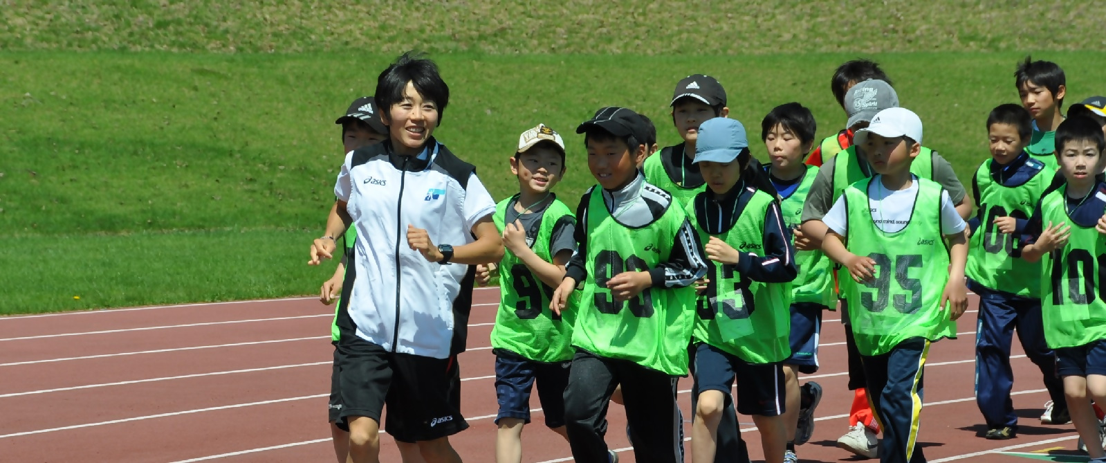 野口みずきさんが子どもたちと陸上競技場を走る写真（2010年）