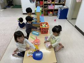 小さな子ども達がおもちゃで思い思いに遊んでいる様子の写真