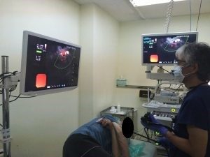 治療台で横向きになっている患者さんの前に立ち内視鏡検査を行っている男性医師の写真