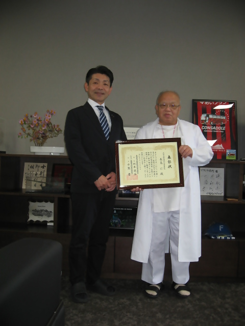 長島院長が渡辺市長にへき地医療貢献者として表彰されたことを報告し、並んで撮影した写真。
