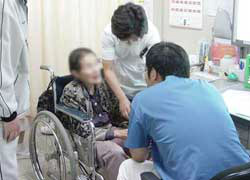 男性医師が車いすに乗った年配の患者さんを診察している様子の写真
