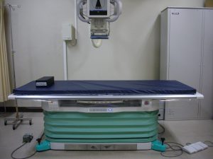 患者が横になるベットがあり、その上にカメラの機械があるFPD臥位撮影装置の写真