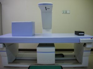 患者が横になるベッドがあり骨密度を測定するX線の機械が設置された写真