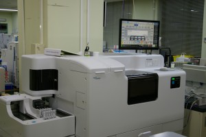 ディスプレイの下に横幅が2メートルくらいある角が丸く施された生化学・免疫検査の機器の写真