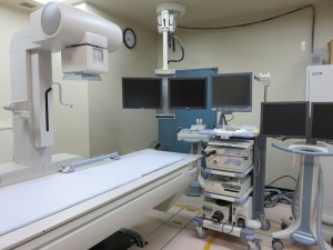 診療台があり、右側に大きなモニターがある第1テレビ室内の写真