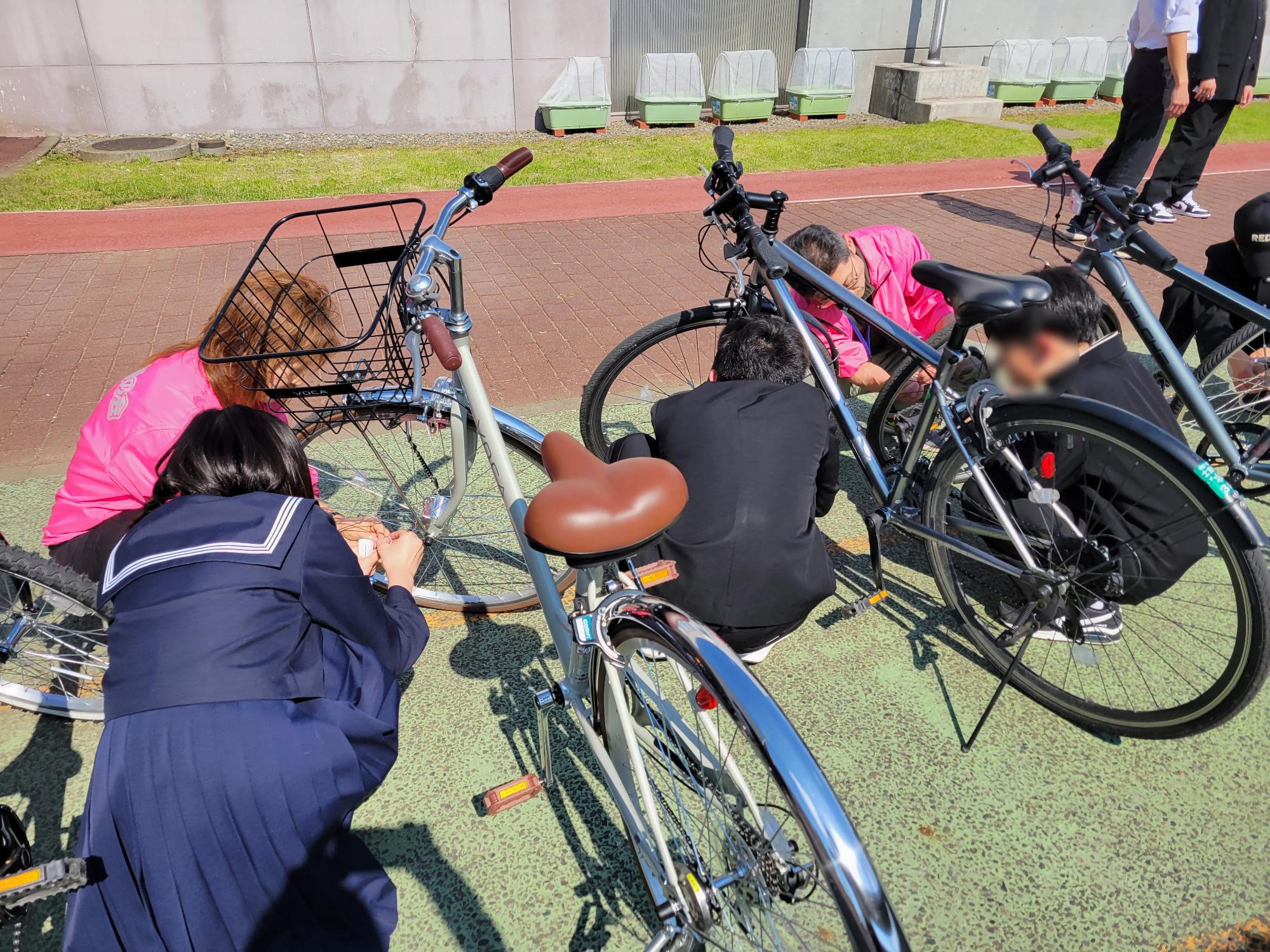 交通安全母の会役員が、中学1年生と一緒に自転車の夜光反射材を取り付けているところ