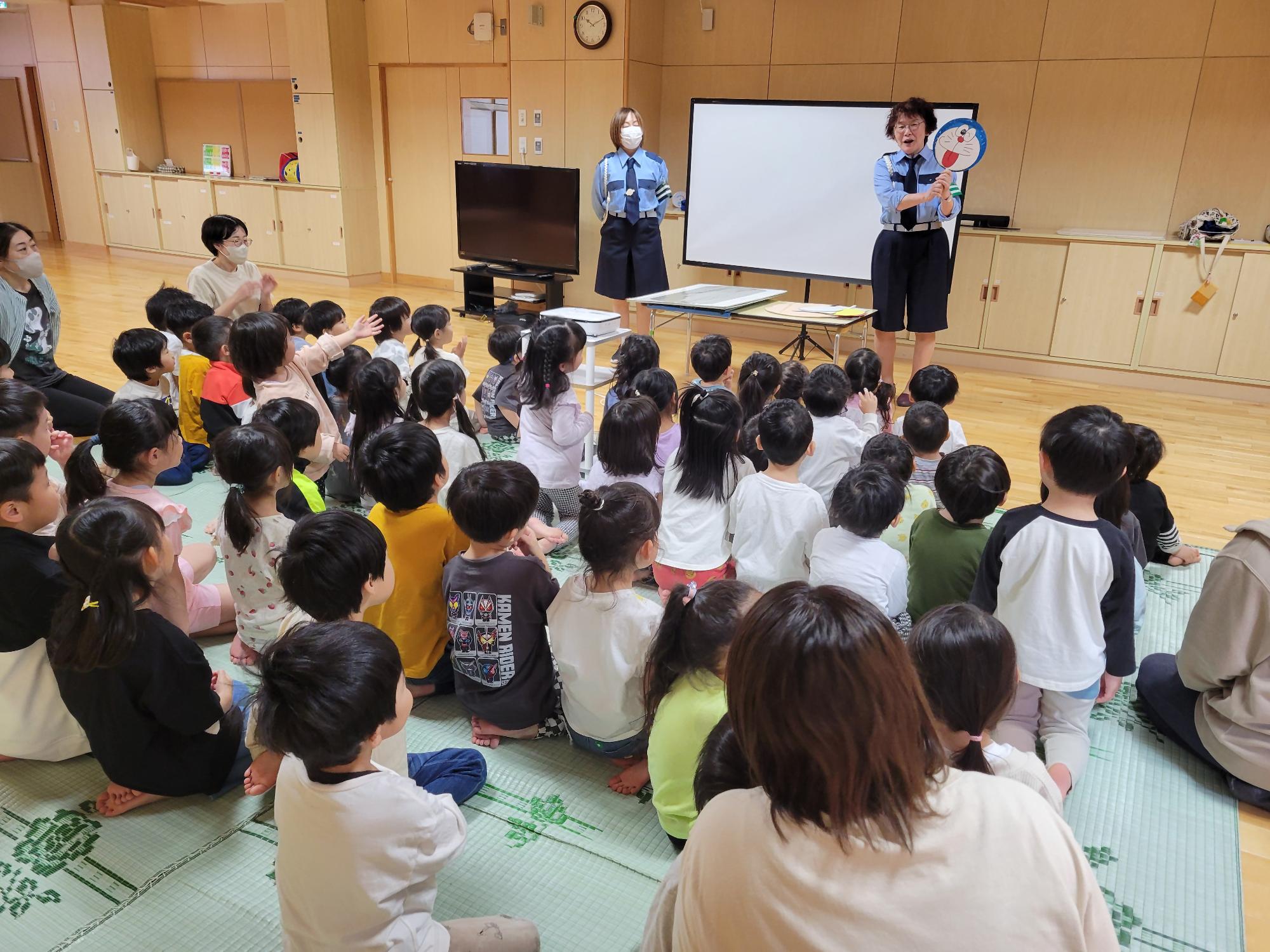 交通安全教育隊が保育園の交通安全教室でキャラクターを使用し信号機の色と意味を伝えているところ