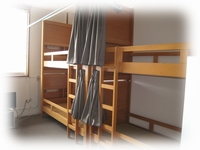 カーテン付きの2段ベッド2つが立て並びに設置されている宿泊室の写真