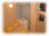 オレンジ色のマットが4枚置かれ、室内全体が木材で作られているサウナ室の写真